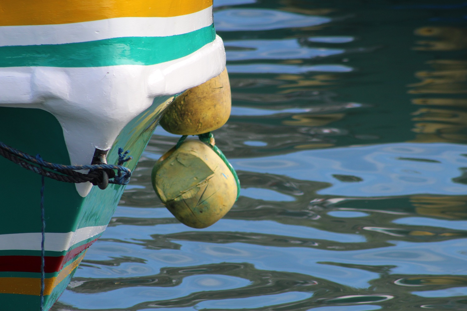 Painted boat hull, ropes and water at a Galapagos harbor.